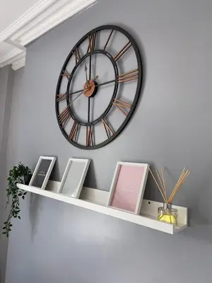 a clock on a wall with a shelf with picture frames at Hall Park Hotel self check in in Workington