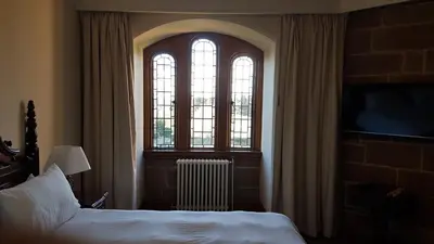 a bedroom with a bed and two windows and a television at Dalston Hall in Carlisle