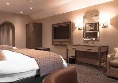 a bedroom with a bed and a desk and a television at Hetland Hall Hotel in Dumfries