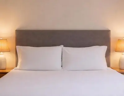 a bed with white pillows in a bedroom with two lamps at Lyzzick in Keswick