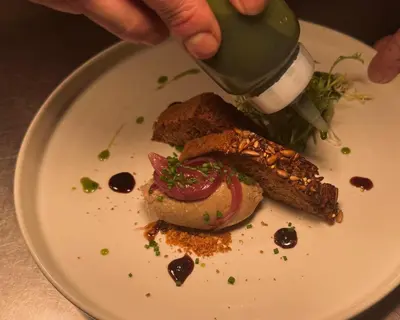 a person is pouring a drink into a plate of food at Lyzzick in Keswick