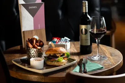 a table with a sandwich and a glass of wine at The Ullswater Inn- The Inn Collection Group in Glenridding