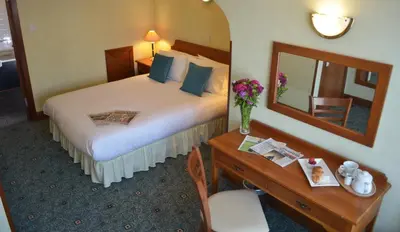 a hotel room with a bed and a desk with a mirror at The Ayrshire and Galloway in Ayr