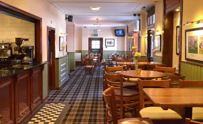 a restaurant with wooden tables and chairs and a bar at The Ayrshire and Galloway in Ayr