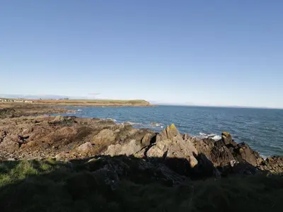 a group of rocks on the shore of a body of water at The Clamshell in Isle of Whithorn