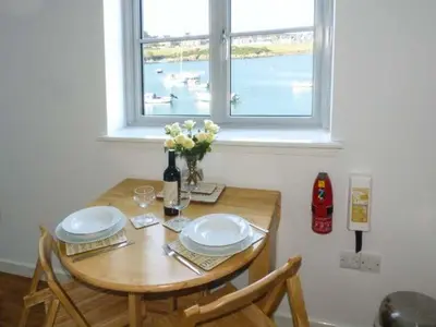 a wooden table with two plates and a window at The Clamshell in Isle of Whithorn
