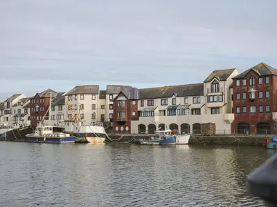 a group of buildings next to a river with boats at Harbour Side in Maryport