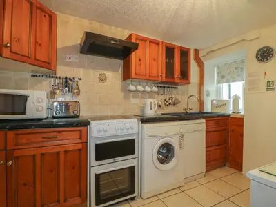 a kitchen with a stove and a washing machine at Derwent Edge in Portinscale