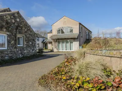 a large stone house with a brick driveway at Skiddaw in Cockermouth