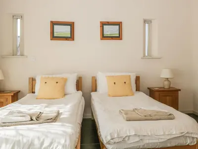 two twin beds in a room with two windows at Skiddaw in Cockermouth
