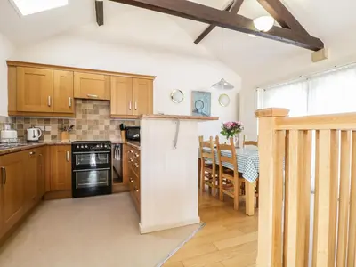 a kitchen with wooden cabinets and a dining room at Skiddaw in Cockermouth