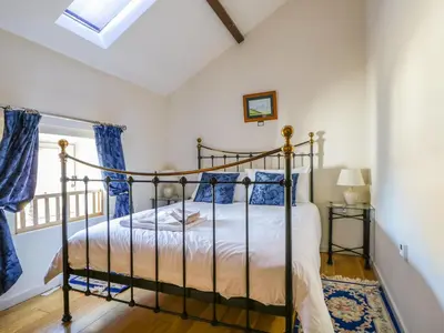 a bedroom with a bed with blue curtains and a window at Beckside in Cockermouth