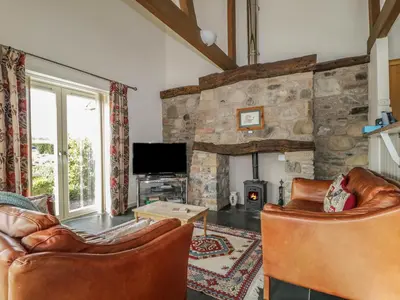 a living room with leather furniture and a stone wall at Buttermere in Cockermouth