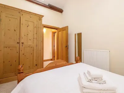 a bedroom with a white bed and wooden cabinets at The Hayloft in Keswick