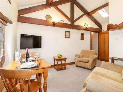 a living room with a table and a tv at The Hayloft in Keswick