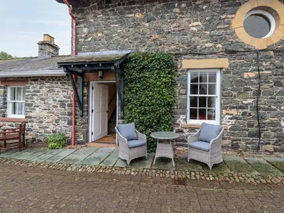 a patio with two chairs and a table in front of a building at The Hayloft in Keswick