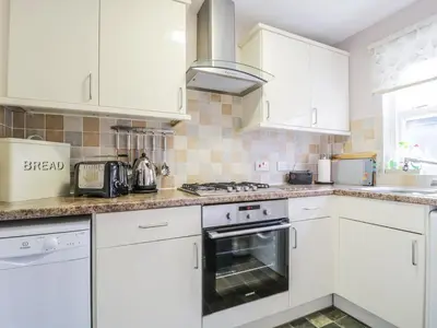 a kitchen with white cabinets and a stove top oven at Swinside Cottage in Keswick