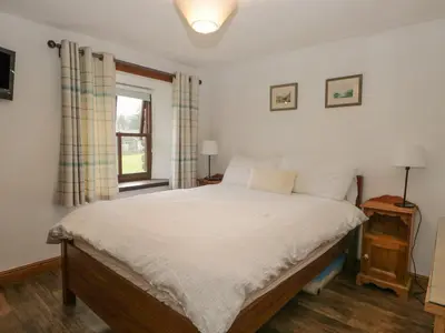 a bedroom with a bed with white sheets and a window at Tanner Croft Cottage in Ambleside