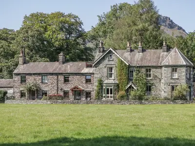 an old stone house with a field in front of it at Tanner Croft Cottage in Ambleside