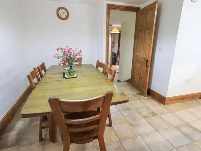 a dining room table with chairs and a vase of flowers at Tithe Cottage in Cockermouth