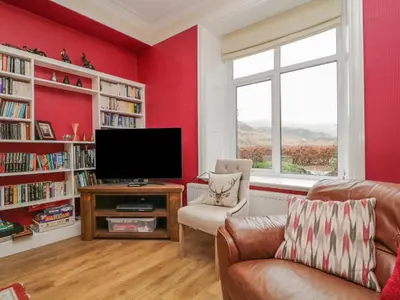 a living room with red walls and a flat screen tv at The Old Vicarage in Thirlmere