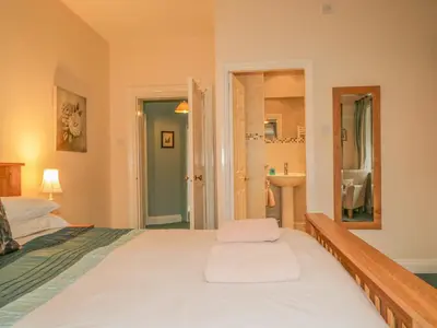 a bedroom with a bed and a bathroom with a sink at The Old Vicarage in Thirlmere