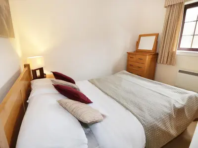 a bedroom with a bed with pillows and a window at Savita Cottage in Girvan
