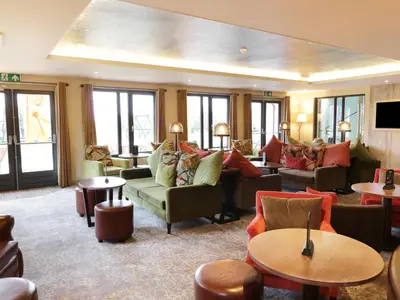 a living room with couches and tables and windows at Savita Cottage in Girvan