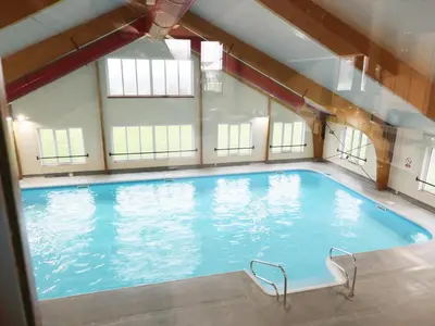 a large swimming pool in a building with windows at Savita Cottage in Girvan