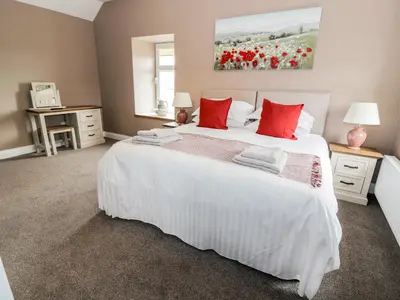 a bedroom with a large white bed with red pillows at Longforth Farm Cottage in Gillespie