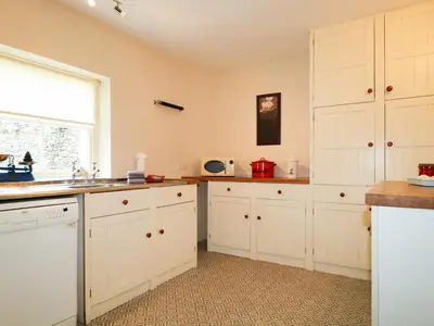 a kitchen with white cabinets and a window at Dale House in Cockermouth
