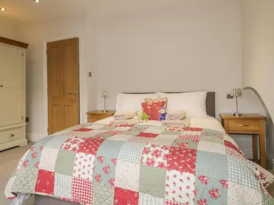 a bed with a red and white quilt on it at Roselea in Keswick