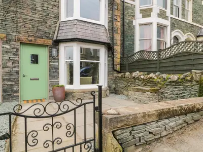 a green door on a brick house with a fence at Roselea in Keswick