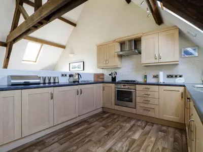 a large kitchen with wooden cabinets and wooden floors at Carpenters Cottage in Cockermouth