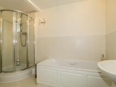 a white bathroom with a shower and a sink at Carpenters Cottage in Cockermouth