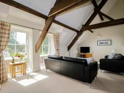 a living room with a black couch and a window at Carpenters Cottage in Cockermouth