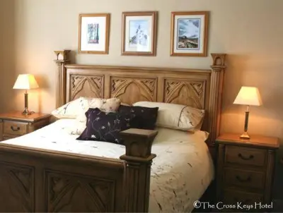 a bedroom with a bed with pillows and two lamps at The Cross Keys Hotel in New Galloway