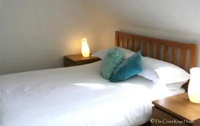 a white bed with two blue pillows and a lamp at The Cross Keys Hotel in New Galloway