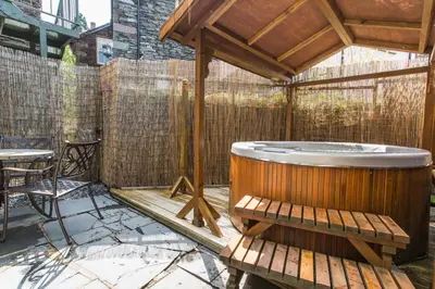a deck with a hot tub and a table at Moss Grove Organic in Grasmere