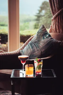 a table with two drinks on a couch at Ravenstone Manor in Keswick