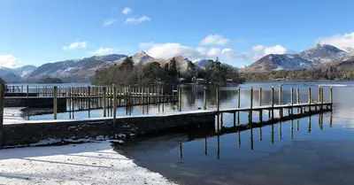 a dock on a lake with mountains in the background at Ravenstone Manor in Keswick