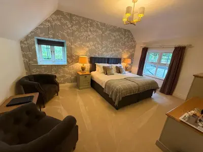 a bedroom with a bed and a couch and a chair at Ravenstone Manor in Keswick