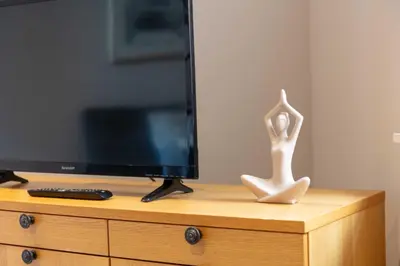 a statue of a woman sitting on a dresser next to a television at Elliot Suite No2 - Donnini Apartments in Ayr