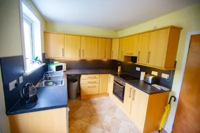 a kitchen with wooden cabinets and a black counter top at Kelpies Cottage in Newton Stewart