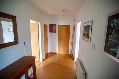 a hallway with white walls and a wooden floor at Kelpies Cottage in Newton Stewart
