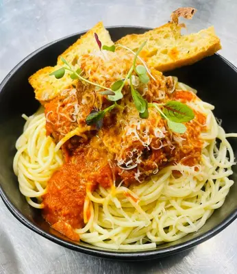 a black bowl of spaghetti with a piece of bread at The Garret Hotel in Kirkcudbright