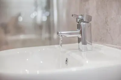 a bathroom sink with water pouring from a faucet at Keld Green House in Seascale