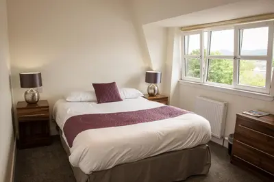 a bedroom with a large bed with two windows at The Birchtree Hotel in Dalbeattie