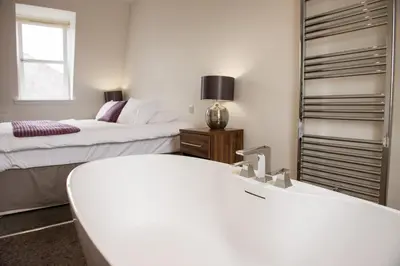 a white bathroom with two beds and a mirror at The Birchtree Hotel in Dalbeattie