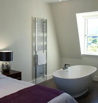 a white bath tub in a bedroom next to a bed at The Birchtree Hotel in Dalbeattie
